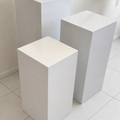 Three white rectangular pedestals on a tiled floor.