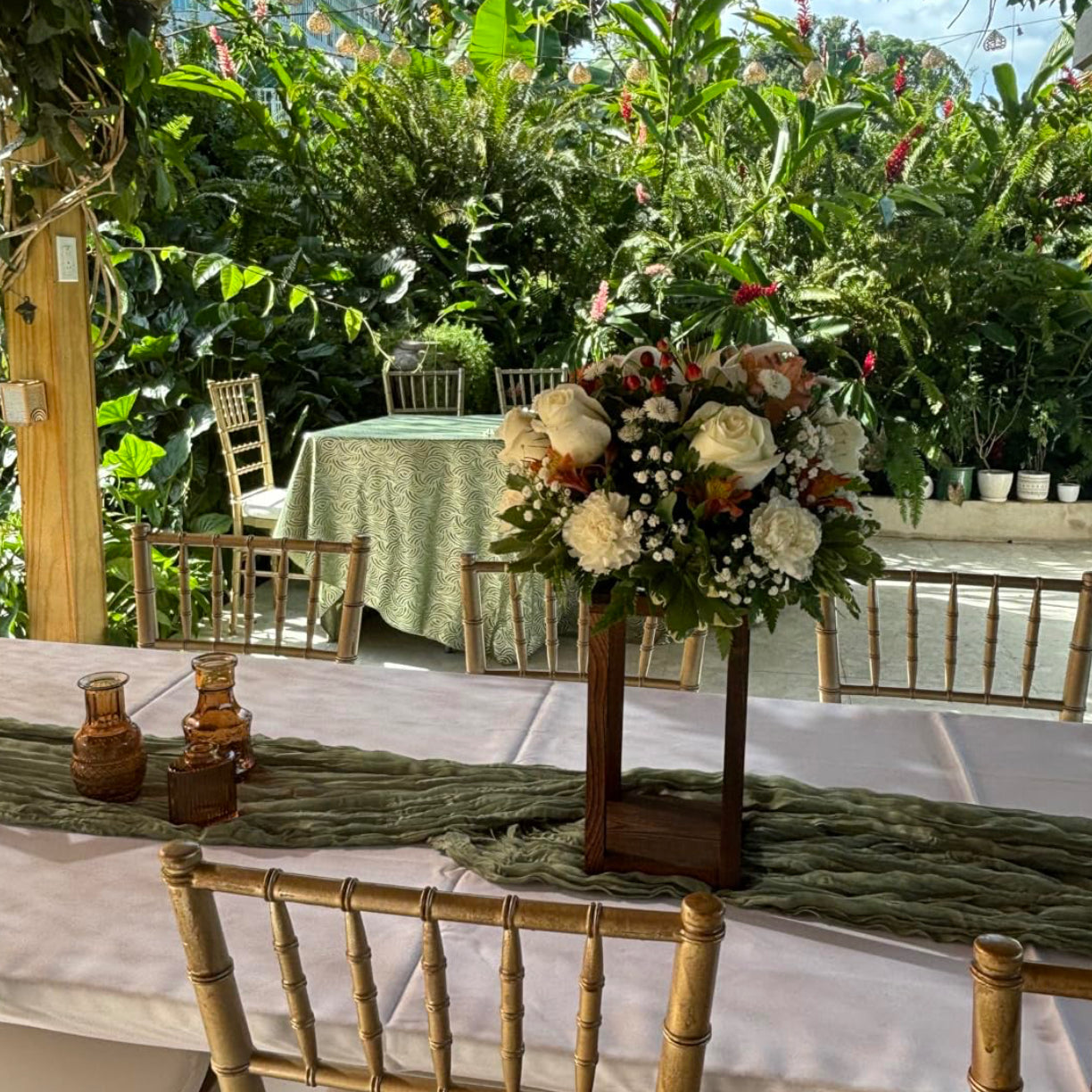 Decorated outdoor table with floral centerpiece and chairs in a garden setting