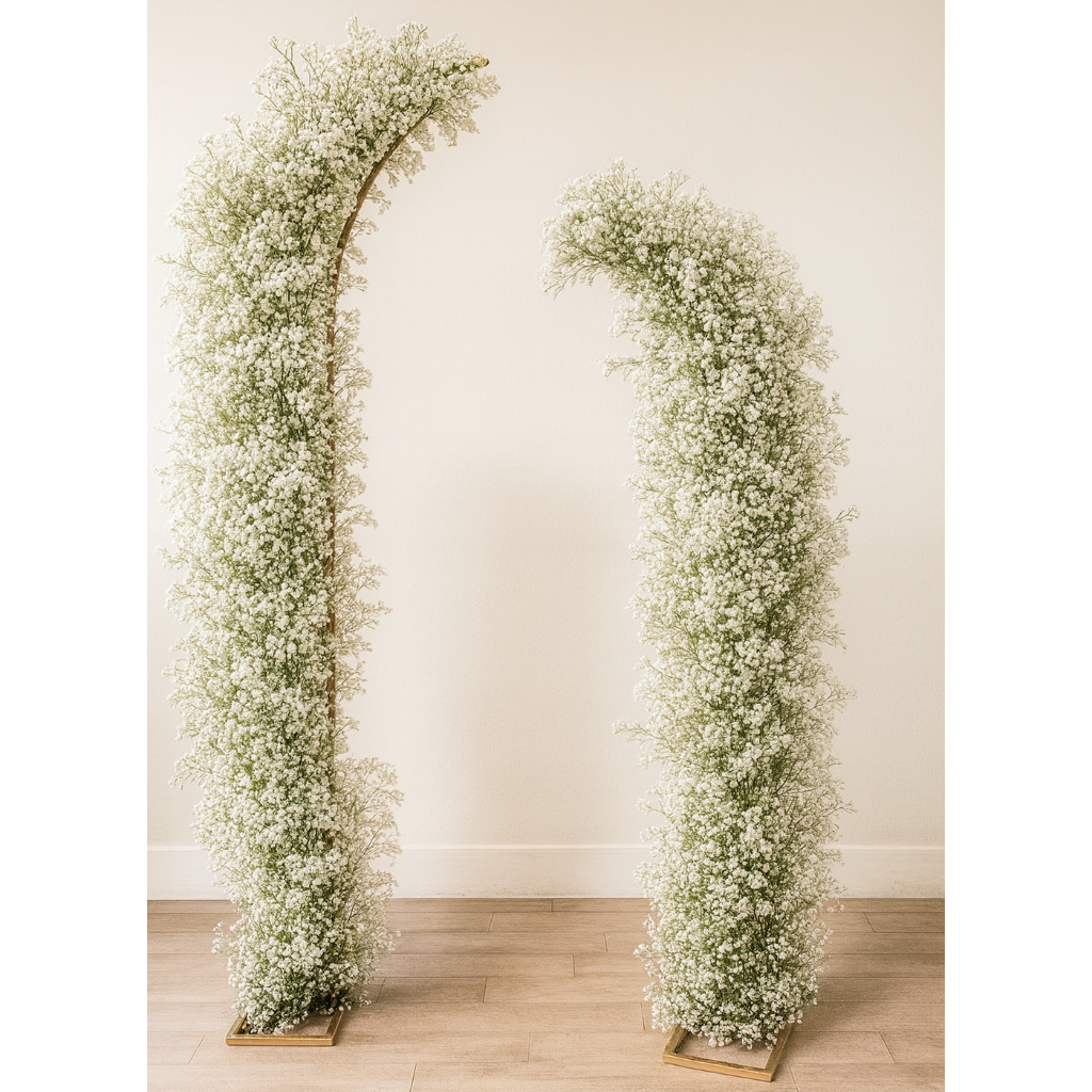 Two floral arches made of baby's breath against a plain wall.