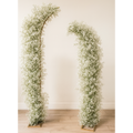 Two floral arches made of baby's breath against a plain wall.