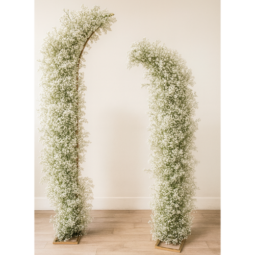 Two floral arches made of baby's breath against a plain wall.