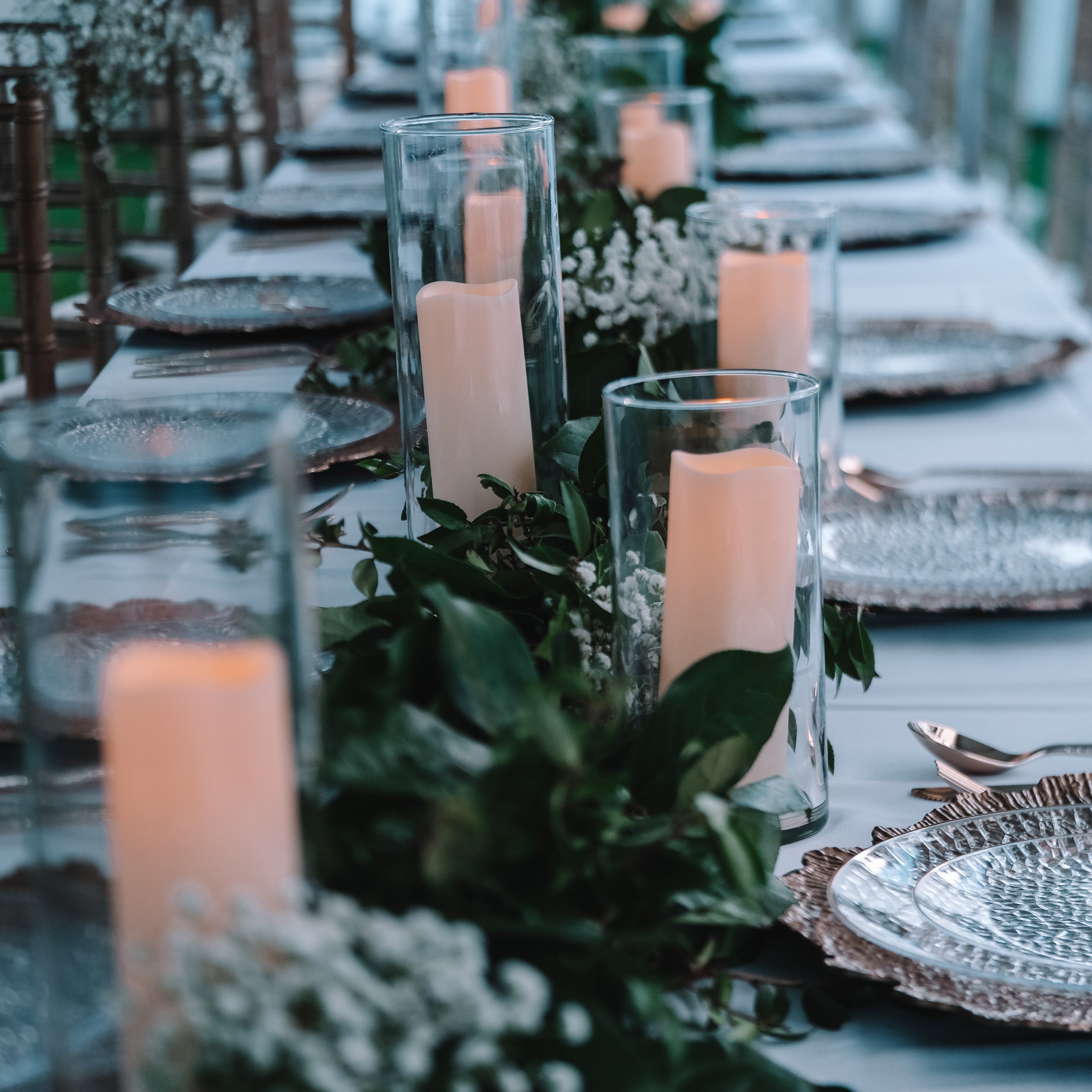 Elegant outdoor wedding table setting with candles and greenery