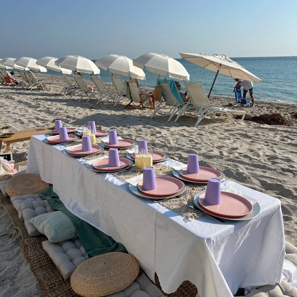 Beach scene with tables, chairs, and umbrellas on a sandy beach.