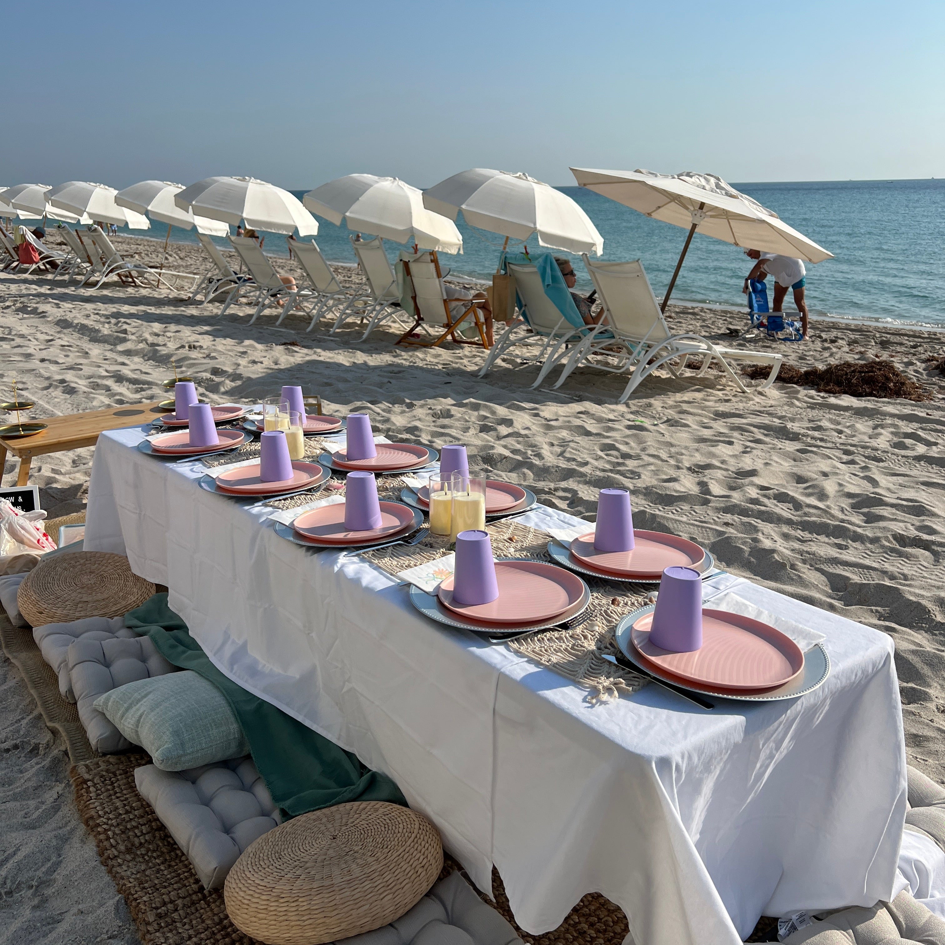 Beach scene with tables, chairs, and umbrellas on a sandy beach.