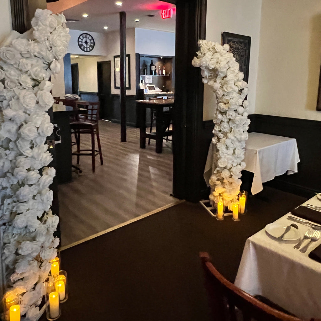 Dining room with a black table and chairs, decorated with white floral arrangements.