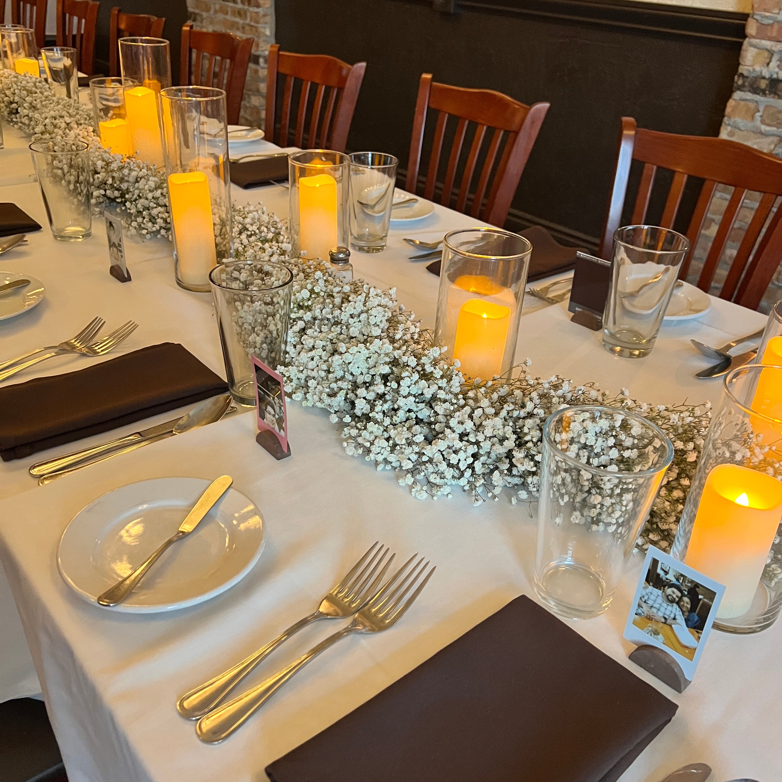 Dining table set with candles, silverware, and a real floral centerpiece.
