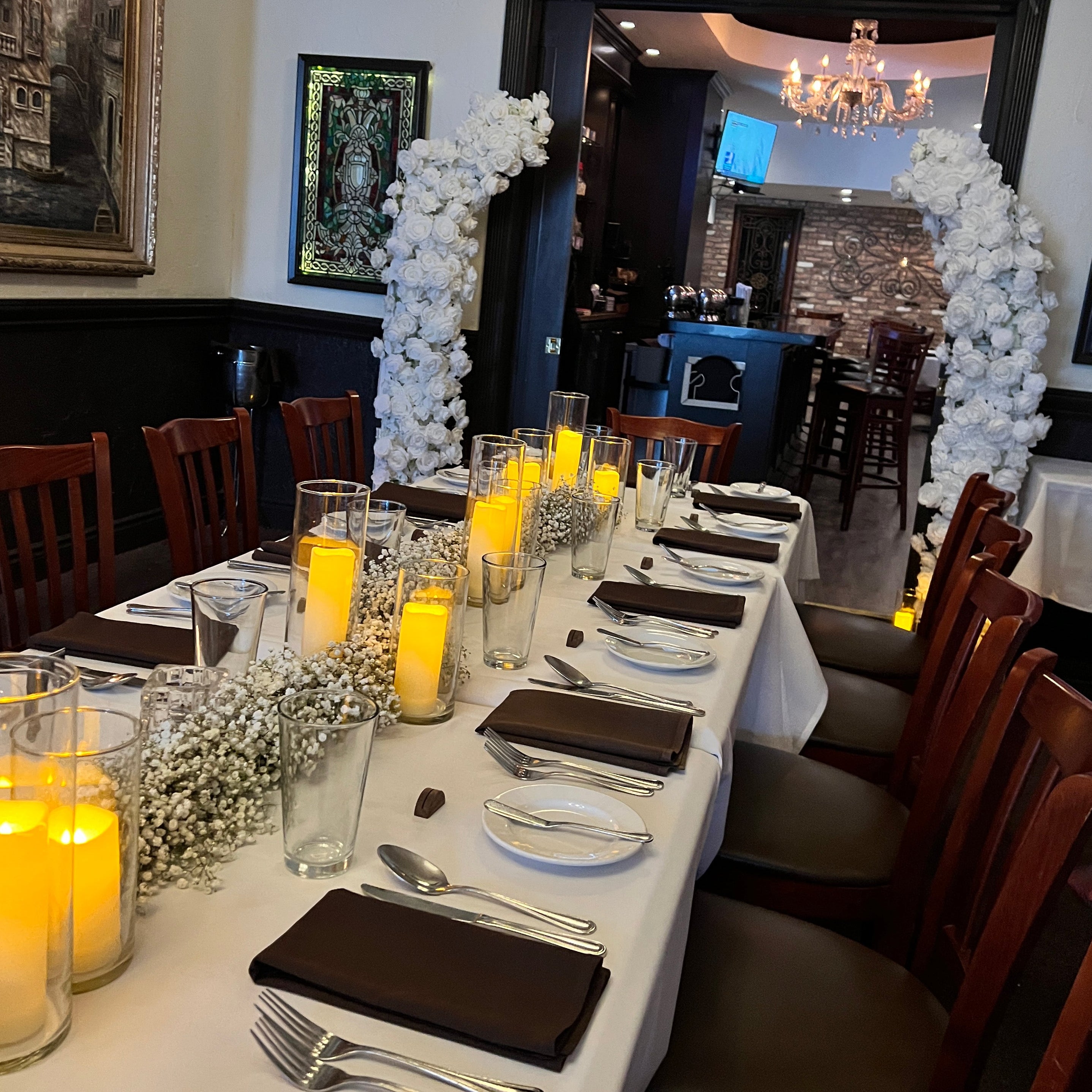 Dining table set with plates, silverware, and candles in a restaurant setting.