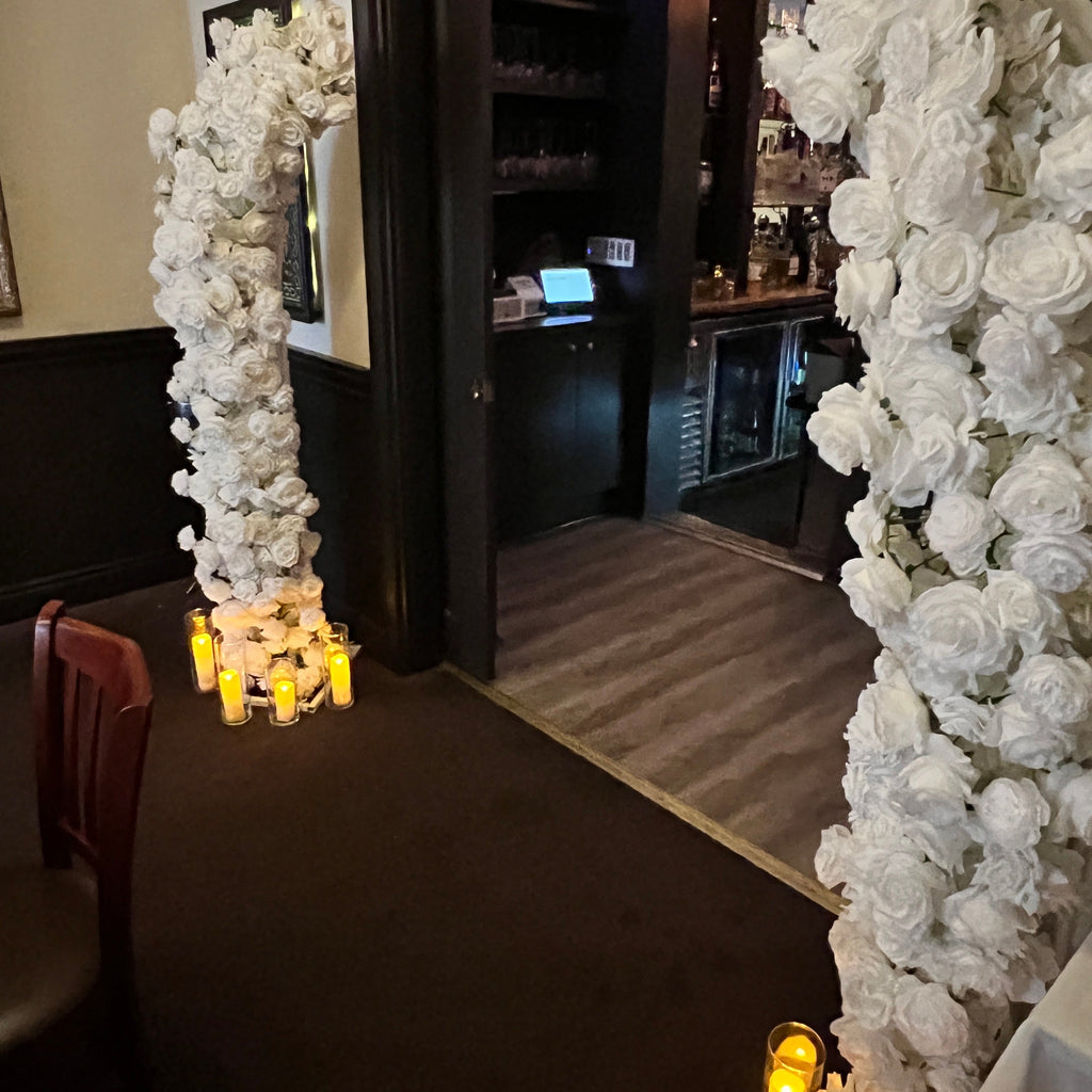 Decorative white floral archway with lights on a dark surface