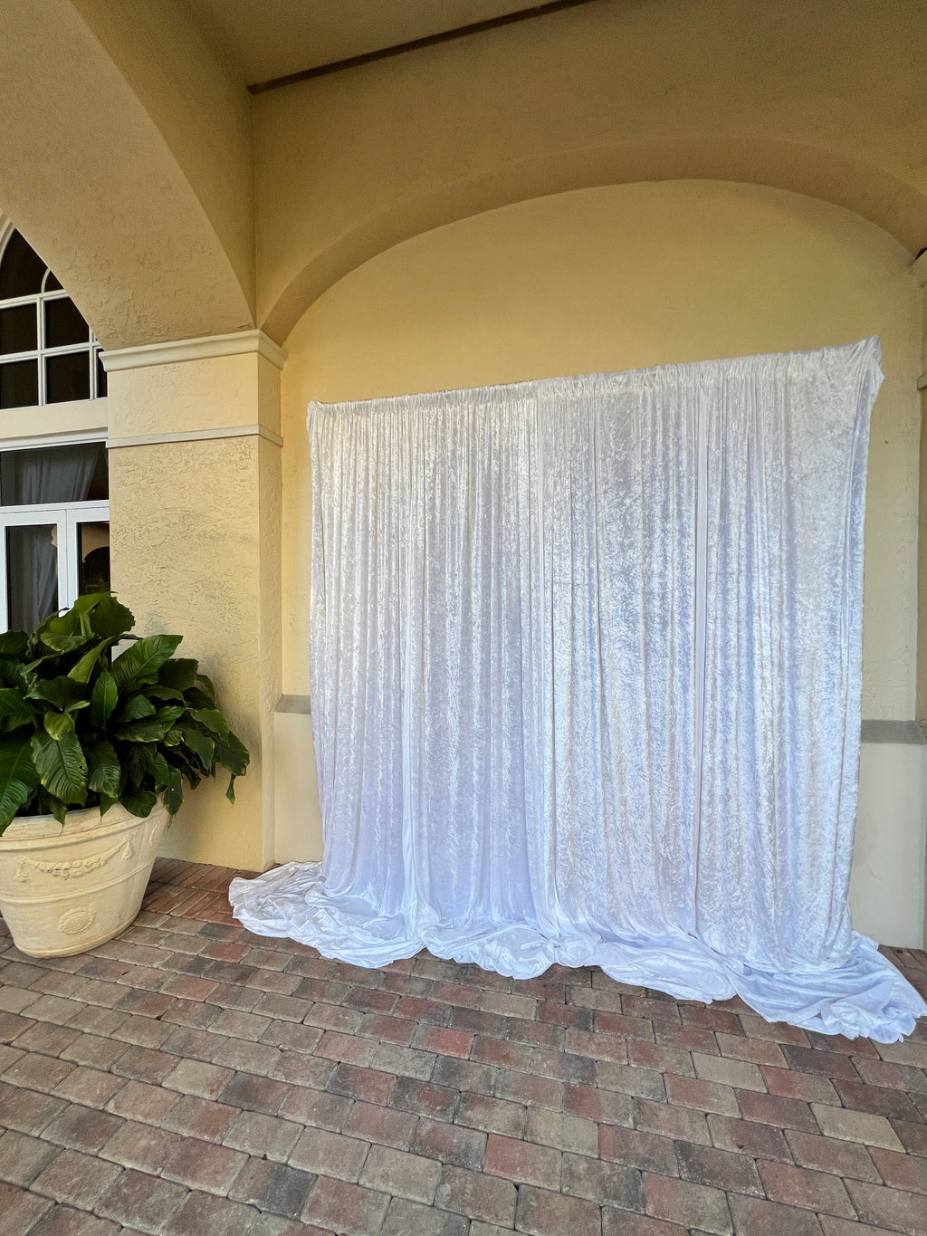 White pleated curtain hanging from a decorative cornice on a wall.