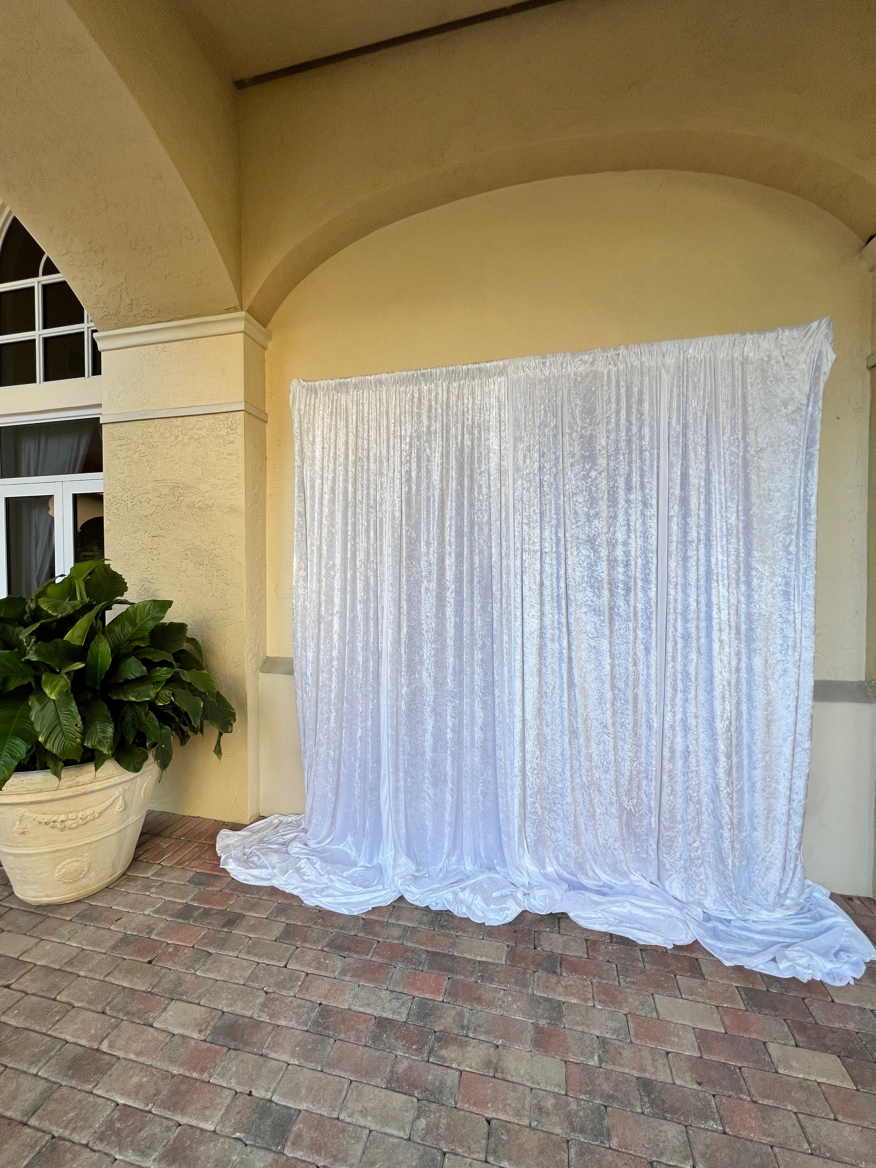 White pleated curtain hanging from a decorative cornice on a wall.