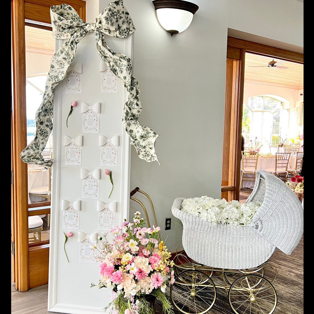 Decorative baby shower setup with a white pram, floral arrangements, and decorative elements.