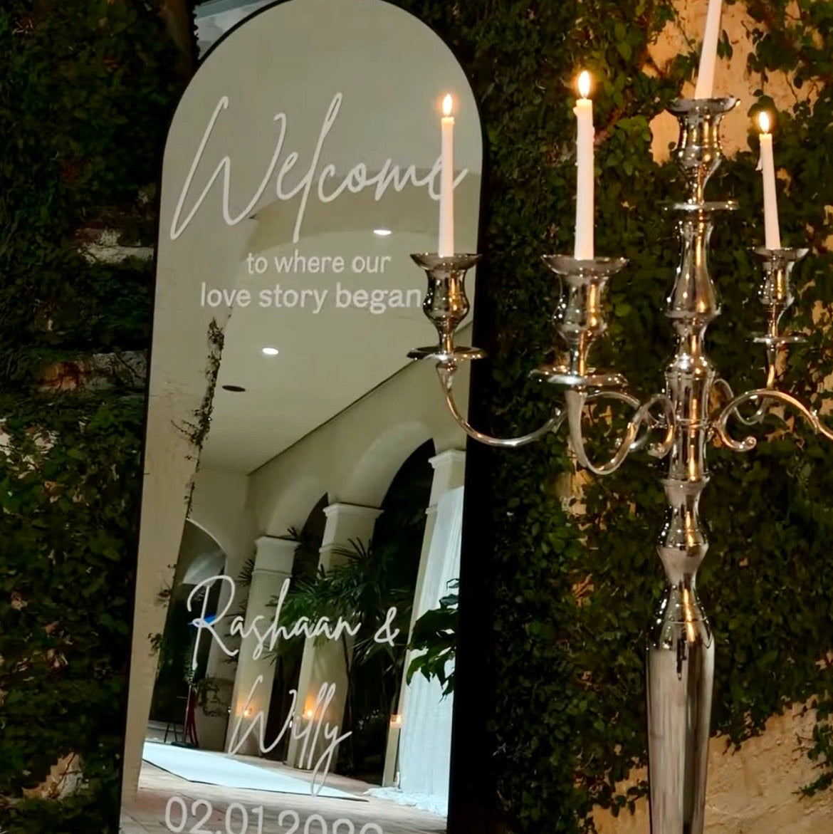 Decorative mirror with personalized text and candelabra in an outdoor setting.