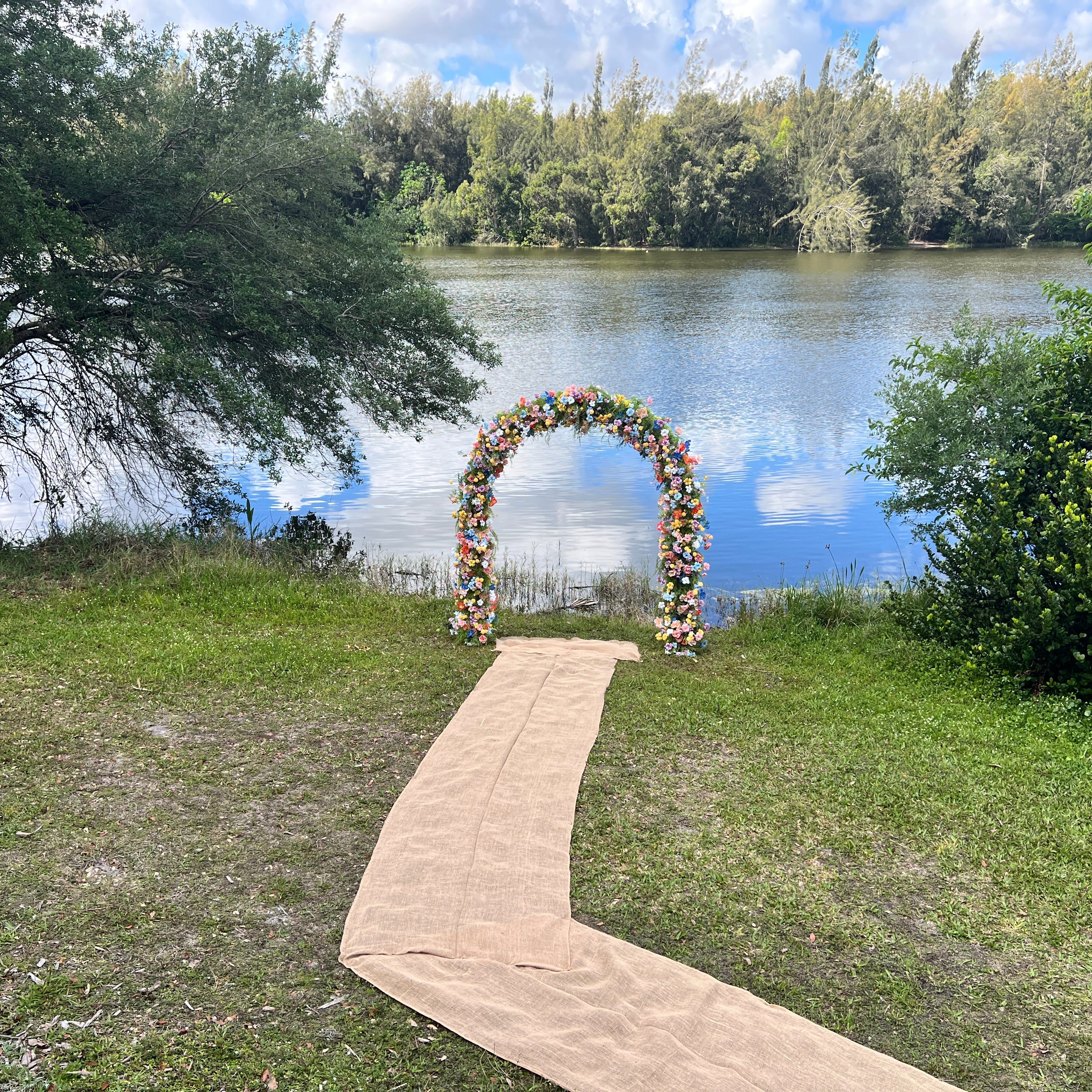 Decorative arch with flowers by a lake on a grassy area