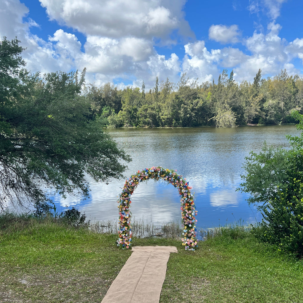 Floral archway by a lake with trees and blue sky in the background
